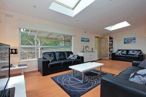 Ein modernes Wohnzimmer mit einem schwarzen Ledersofa, einem weißen Couchtisch und einem großen Fenster, das natürliches Licht hereinlässt.