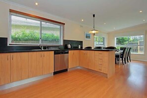A modern kitchen with wooden cabinets, a black countertop, and a built-in dishwasher.