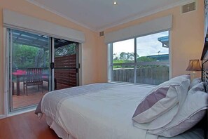 Ein Schlafzimmer mit einem großen Bett, einer Schiebetür zum Balkon und Blick ins Freie.