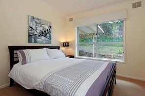 Ein Schlafzimmer mit Bett, Fenster und einem Bild an der Wand.