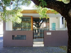 A building with a modern design, featuring a large glass window and a metal gate.
