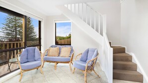 A balcony with wicker chairs and a view of a wooden deck and trees. - Shirl's By The Sea - beach at your doorstep (Gerroa)