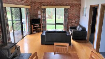 A living room with a fireplace, a sofa, a television, and a dining table with chairs.