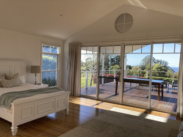 A bedroom with a bed, a nightstand, a lamp, and a view of an outdoor deck.