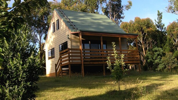 A wooden cabin with a sloped roof, a balcony, and a small porch area. - 2 Night Accommodation Package (GEMBROOK)