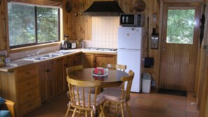 A wooden kitchen with a dining table and chairs, a refrigerator, a microwave, and a window. - 2 Night Accommodation Package (GEMBROOK)