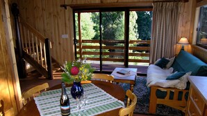 A wooden interior with a dining table set for two, a sofa, and a staircase. - 2 Night Accommodation Package (GEMBROOK)