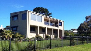 A two-story building with a flat roof, large windows, and a balcony on the second floor.