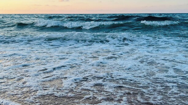 A beach with waves and a clear sky.