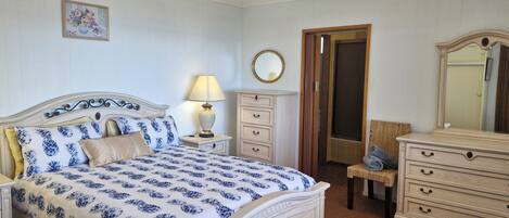 A bedroom with a bed, nightstand, dresser, and a mirror.