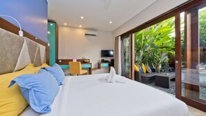 Een hotelkamer met een groot bed, een bureau, een televisie en een schuifdeur naar een tuin.