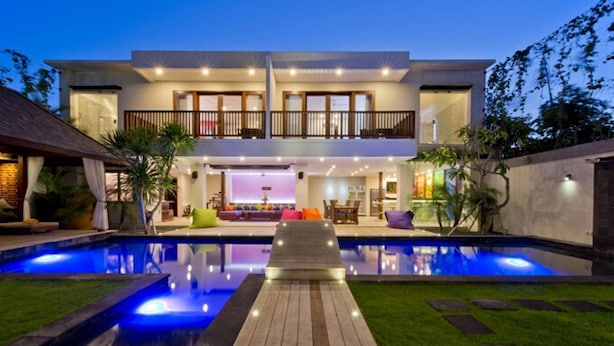 Een modern herenhuis met zwembad, overdekt terras en een verzorgd gazon.