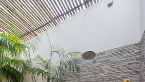 Een moderne badkamer met een stenen muur, een houten plafond en een kleine plant.