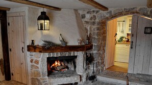 Una chimenea de piedra con fuego, un repisa de madera y un farol colgante.