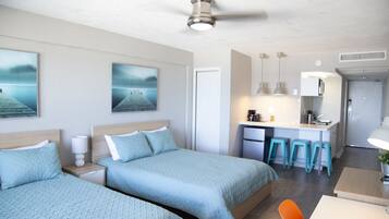 Quarto de hotel moderno com duas camas, uma cozinha compacta e área de jantar.