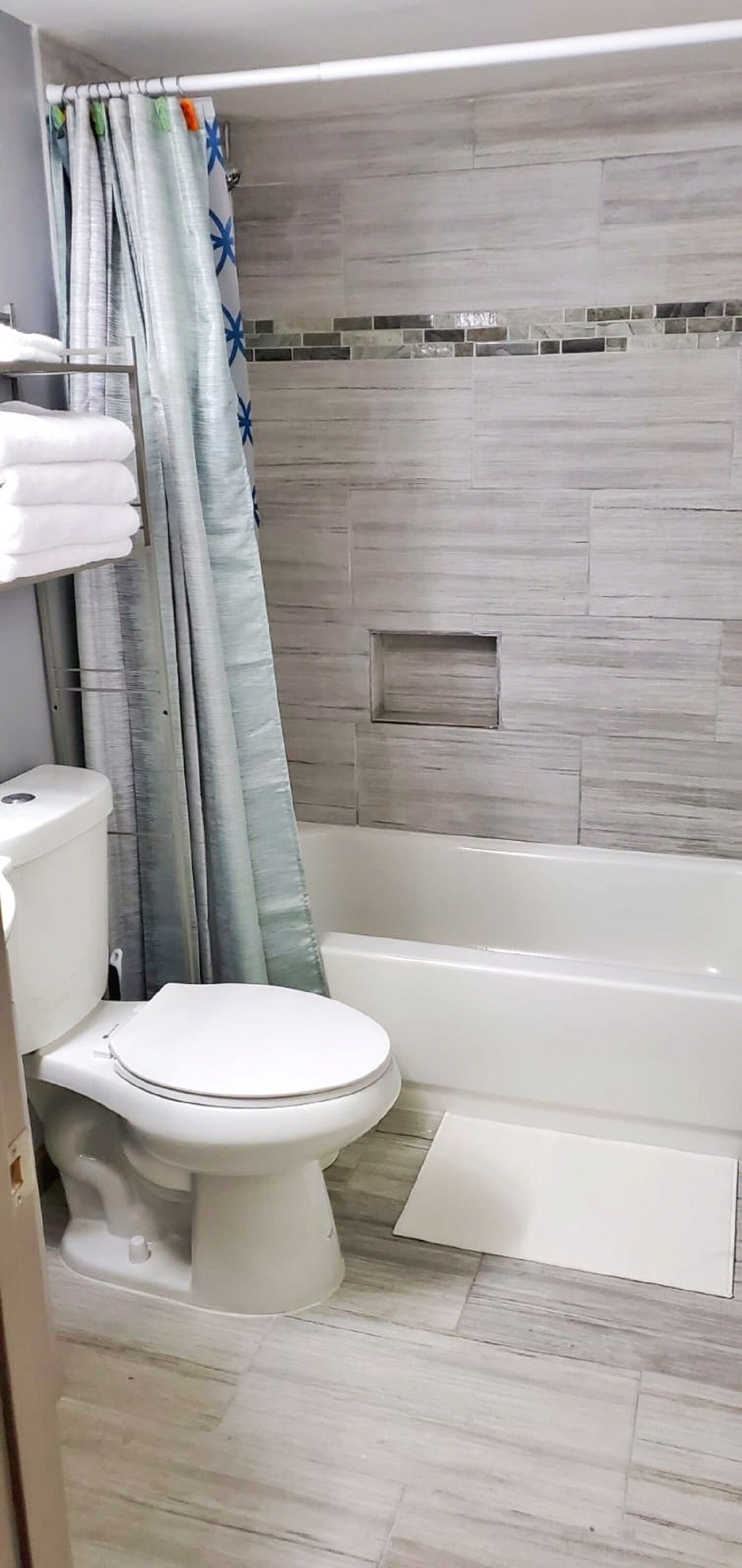 Et badeværelse med toilet, badekar og bruseforhæng.
