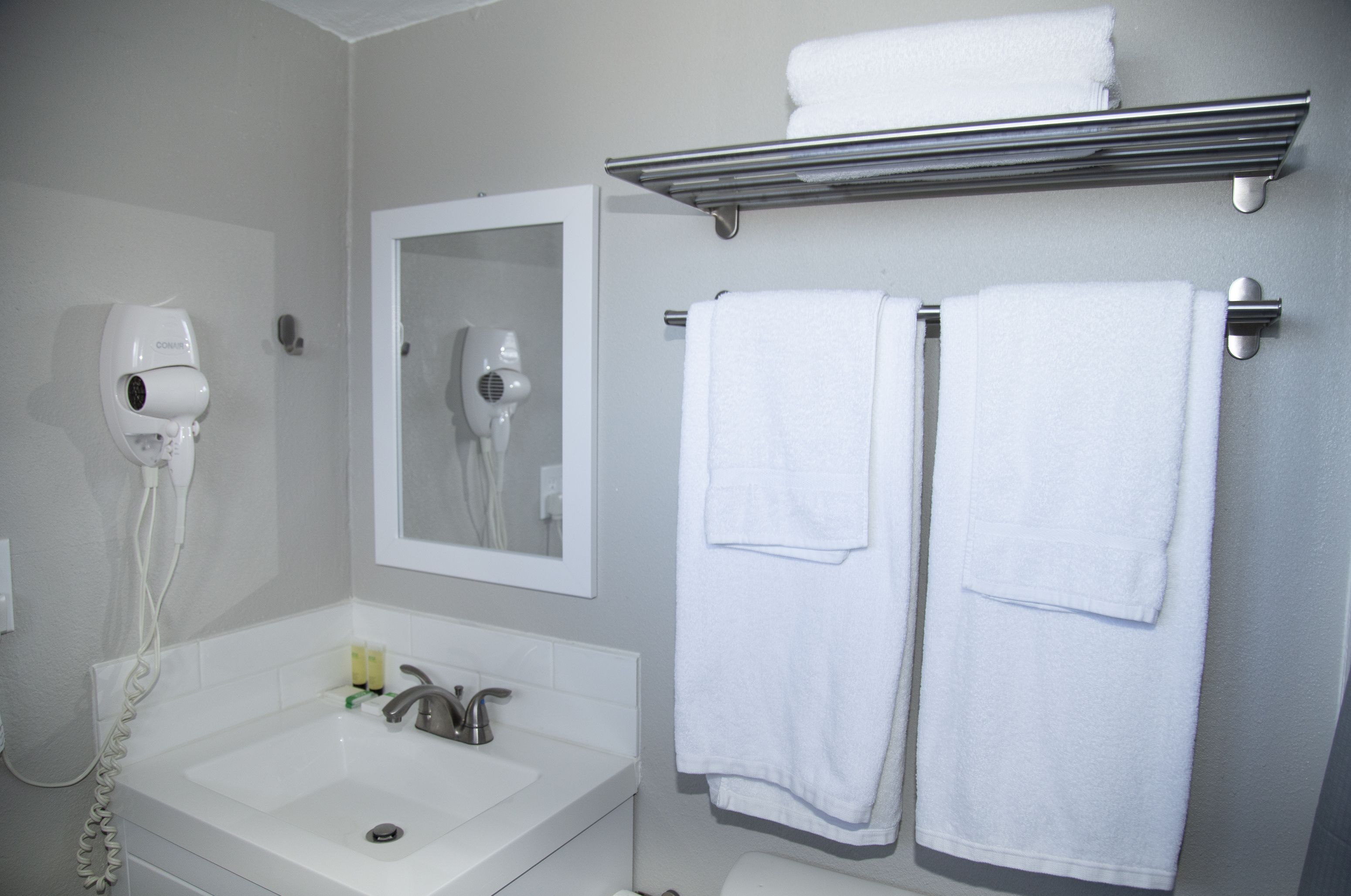 A bathroom with a sink, a hairdryer, and two towels hanging on a rack.