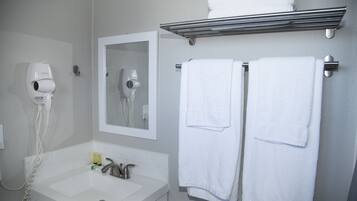 A bathroom with a sink, a hairdryer, and two towels hanging on a rack.