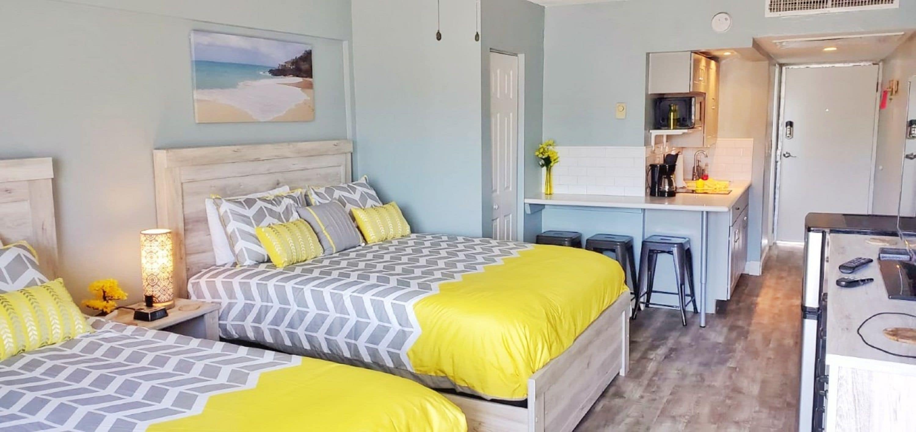 A bedroom with two beds, a small kitchenette, and a bathroom.