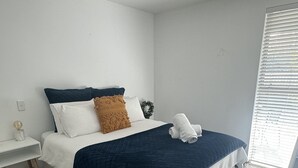 A bedroom with a bed, a desk, and a window with blinds. - Relax, unwind and enjoy the views from this unbeatable lakeside location. (Two Mile Bay (2 Mile Bay))