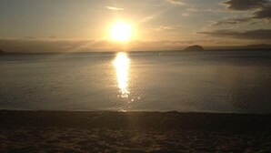 A beach scene with the sun reflecting on the water, a sandy shore, and distant landforms. - Relax, unwind and enjoy the views from this unbeatable lakeside location. (Two Mile Bay (2 Mile Bay))