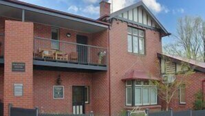 Un immeuble de deux étages en briques, doté d’un balcon à l’étage supérieur.