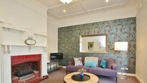 Un salon avec une cheminée, un canapé, une table basse et un mur décoré d’un motif.
