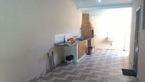 Una cocina estrecha con piso de baldosas, pared de ladrillo y un lavamanos.