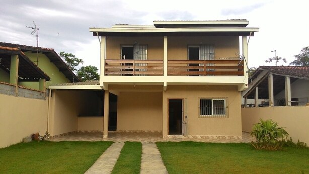Una casa de dos pisos con balcón, puerta principal y una ventana pequeña.