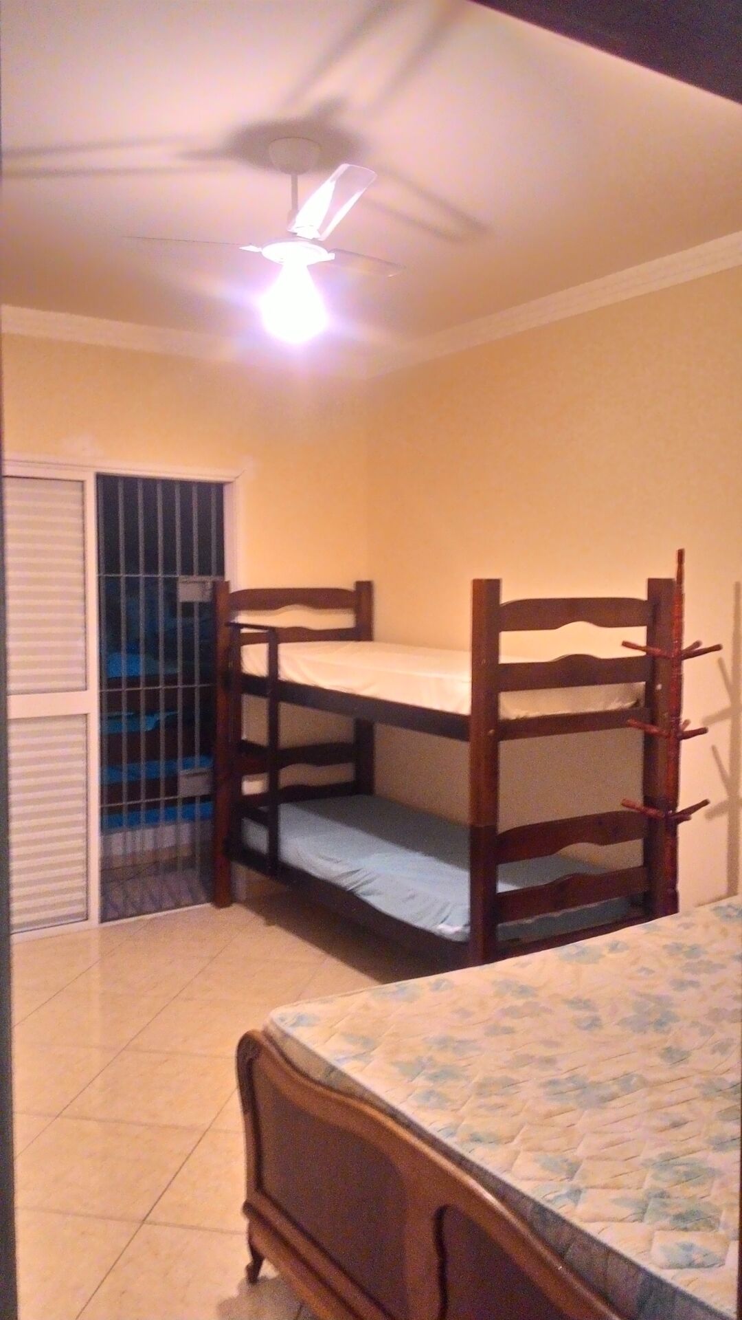 A room with two bunk beds, a ceiling fan, and a door leading to a balcony.