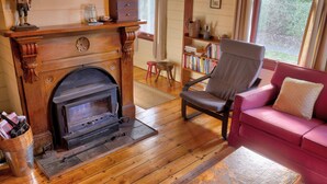 Una habitación acogedora con chimenea de madera, un sofá rojo y una estantería llena de libros.