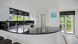 Una cucina moderna con un'isola grande, un frigorifero e una finestra che si affaccia sul verde.
