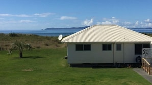 A small, single-story building with a sloped roof, a satellite dish, and a grassy lawn. - Seabed Bach Tokerau Beach (Karikari Peninsula)