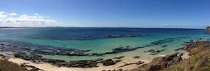 A coastal landscape with clear turquoise waters, rocky outcrops, and sandy beaches.