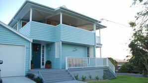 Une maison à deux étages avec un porche à l’avant, un garage et un petit jardin devant.