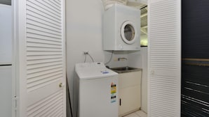 A compact laundry room with a washing machine, a dryer, and a sink.