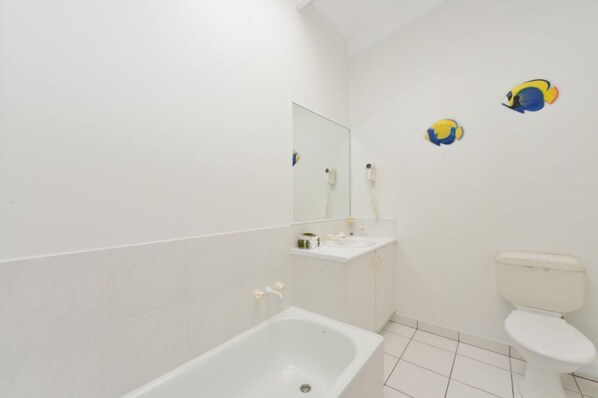 Un baño con bañera, inodoro y espejo.