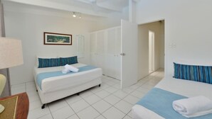 A hotel room with a bed, a chair, a lamp, a picture on the wall, and a door leading to another room.