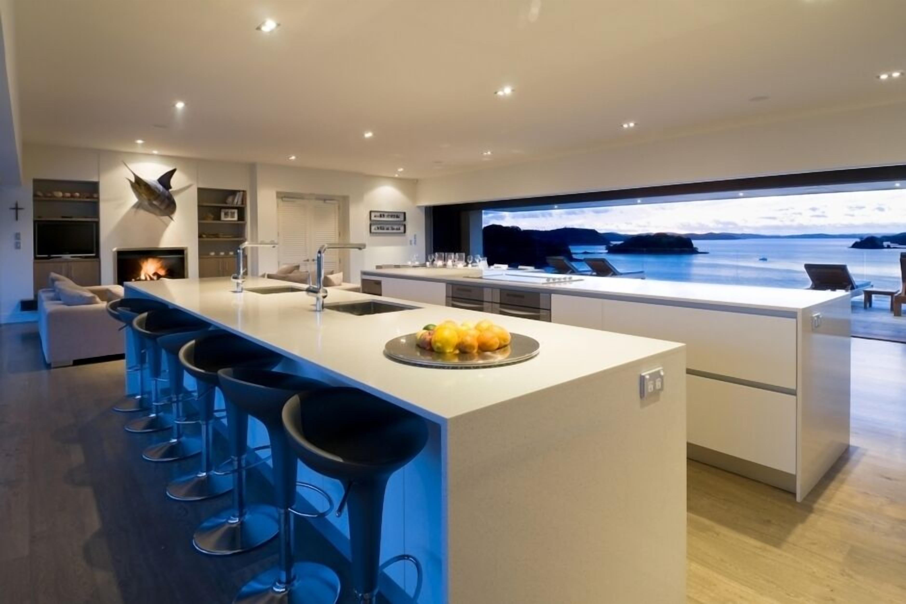Une cuisine moderne dotée d’un grand îlot central, de tabourets de bar et offrant une vue sur la mer.