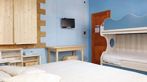 Una habitación con literas, un escritorio de madera, un televisor en la pared y una puerta de diseño peculiar.