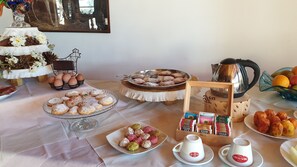 Una mesa de buffet con diversos alimentos, entre ellos pasteles, frutas y bebidas.