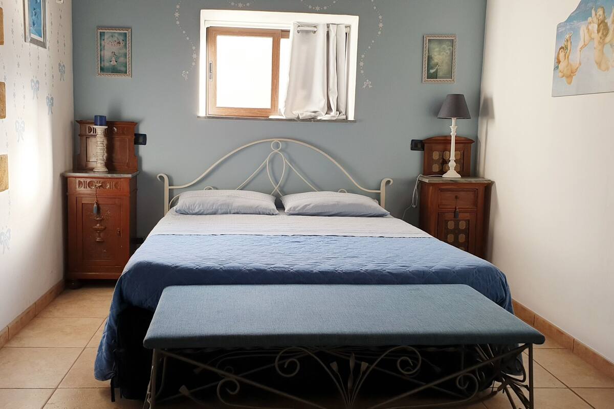 Un dormitorio con cama, mesita de noche, cómoda, ventana con cortinas y pared decorada con estrellas.
