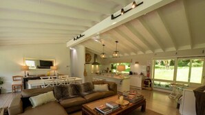 A spacious living area with a large sofa, a coffee table, and a kitchen in the background.
