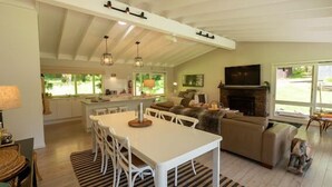A spacious living area with a high ceiling, a fireplace, and a large TV.