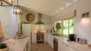 A modern kitchen with white cabinets, a stainless steel oven, and a window providing natural light.