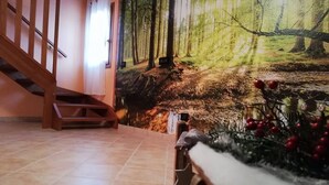 A room with a staircase, a mural of a forest scene, and a Christmas tree with red berries. - Karingo House (Fratta Polesine)