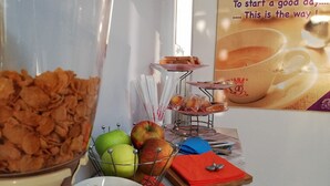 A breakfast setup with cereal, apples, and a tiered stand with pastries. - Karingo House (Fratta Polesine)