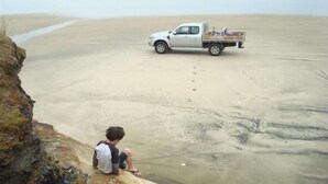 A beach with a white pickup truck parked on the sand.