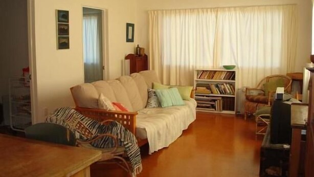 A cozy living room with a sofa, a bookshelf, and a dining area.