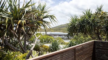 Relax in a serene outdoor seating area surrounded by lush greenery and a picturesque coastal view.